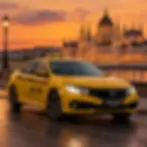 Studio photography of a bright yellow taxi car parked by a river bank. The Hungarian Parliament Building glows in the golden hour sunset background, creating a scenic and travel-inspired atmosphere.