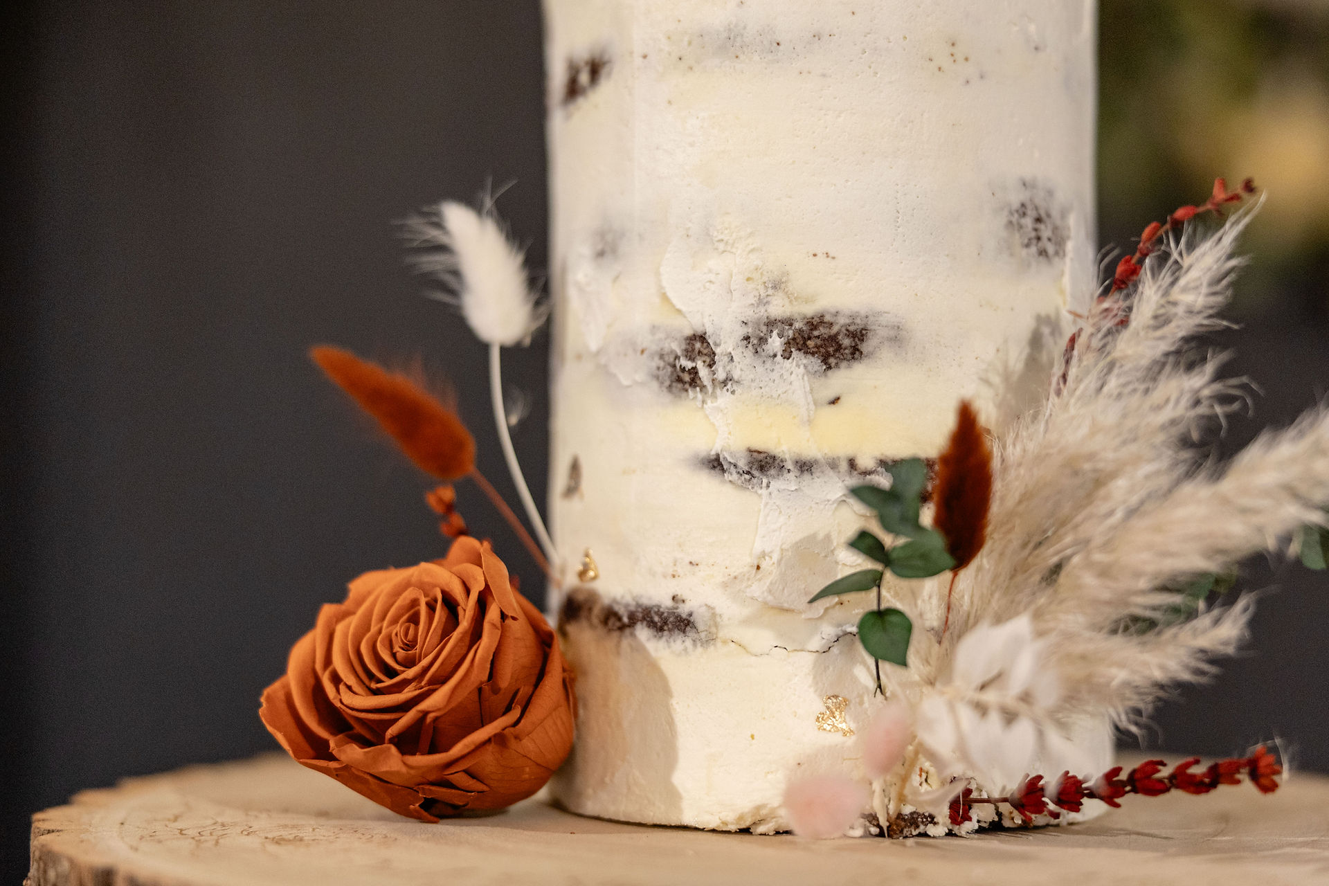 Close-up of preserved flowers decorating a rustic semi-naked wedding cake.