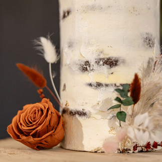 Close-up of preserved flowers decorating a rustic semi-naked wedding cake.