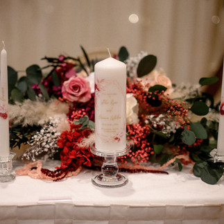 Unity candle display with preserved floral arrangement for a wedding ceremony.