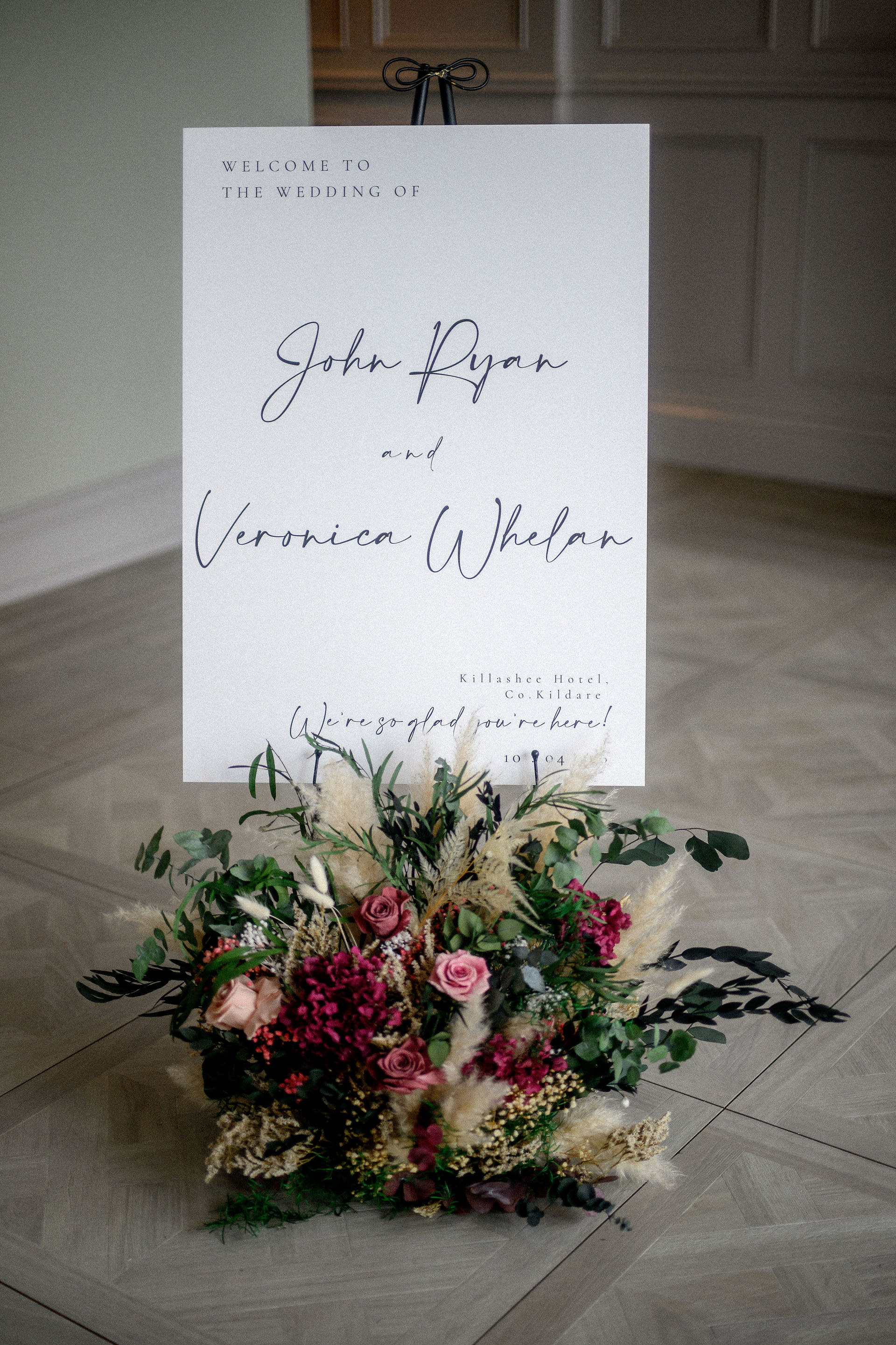 Wedding welcome sign decorated with a floral floor arrangement in blush, berry and white preserved f
