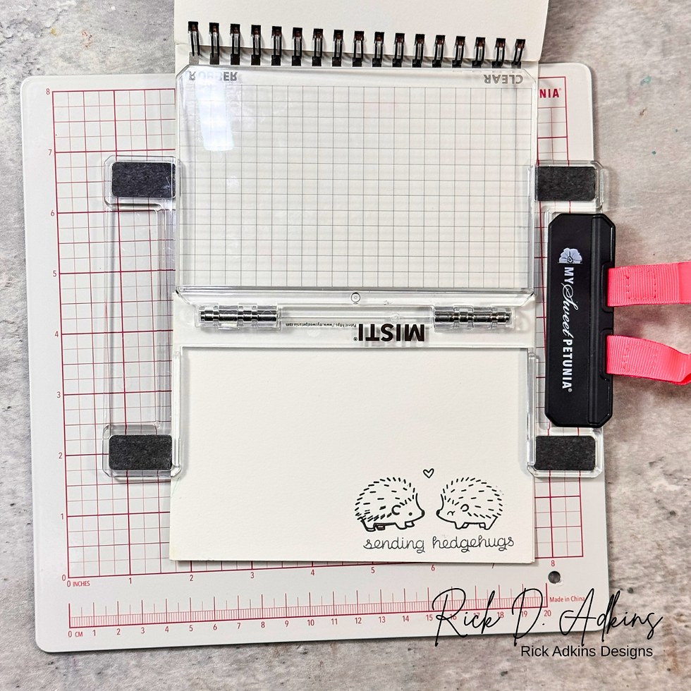 Cardmaking tool with grid overlay, pink accents, and stamped hedgehogs on paper saying "sending hedgehugs." Rick Adkins Designs logo.