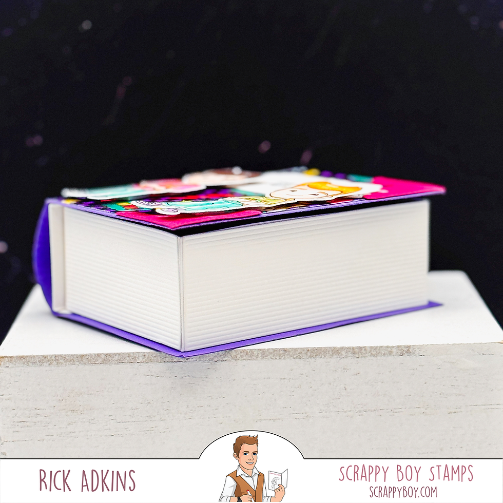 A colorful book gift box with a vibrant cover sits on a white surface. Text reads "Rick Adkins" and "Scrappy Boy Stamps" with a logo below.