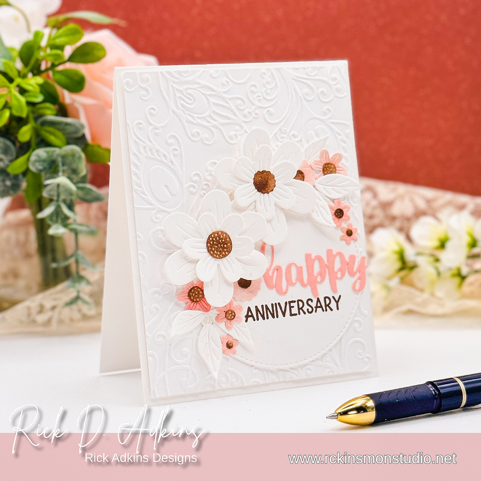White embossed anniversary card with white and pink flowers. Text reads "happy anniversary". Pen and flowers in background.