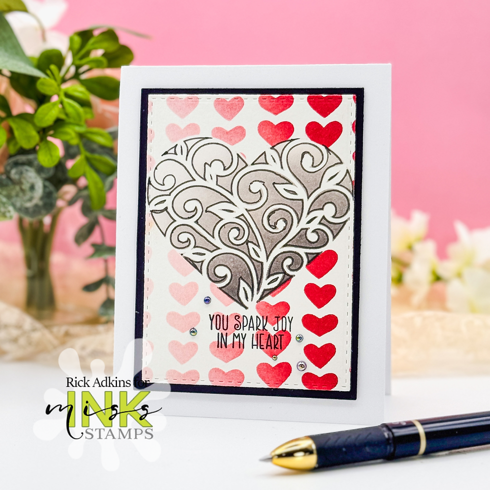 Card with ornate gray heart design over pink and red hearts. Text reads "You spark joy in my heart." Pink background, plant in view.