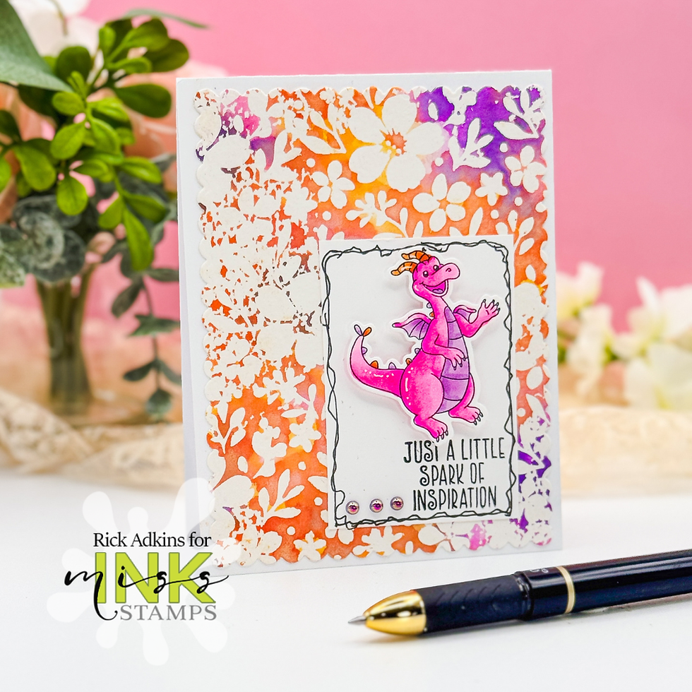 Pink dragon card with "Just a little spark of inspiration" text. Vibrant orange and purple floral border. Pen and greenery in background.