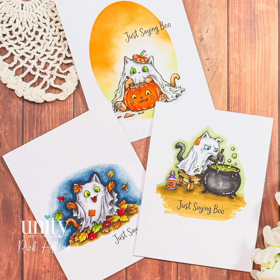 Three Halloween cat cards on a wood table, with Just Saying Boo text, a cat hugging a pumpkin, a ghost cat, and a cauldron cat.