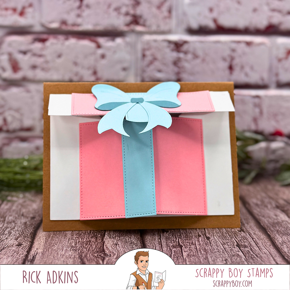 Card with pink and blue gift design, set against a brick backdrop. Branding reads Rick Adkins, Scrappy Boy Stamps, scrappyboy.com.