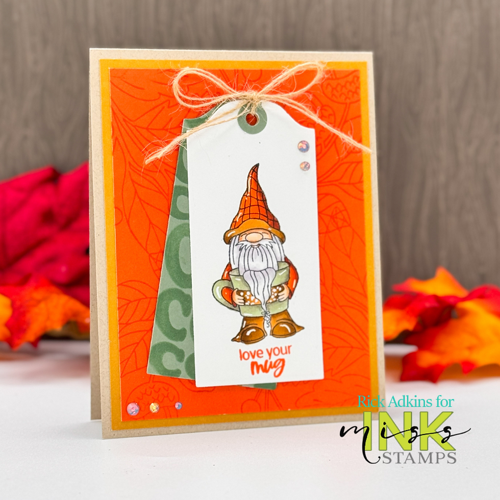 A handmade card with a gnome holding a mug on a tag, "love your mug" text. Orange, green colors. Autumn leaves in the background.