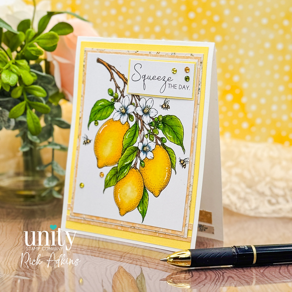 Handmade lemon greeting card with flowers and bees, reading Squeeze the Day, on a table beside a pen and plant.