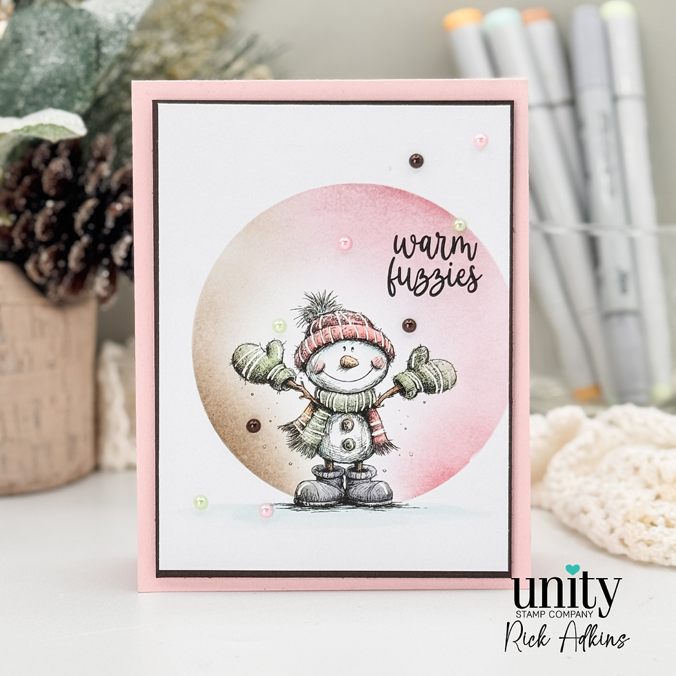 A snowman in a scarf and hat waves on a card. Text says "warm fuzzies." Background has pinecones and markers. Soft pink and tan tones.