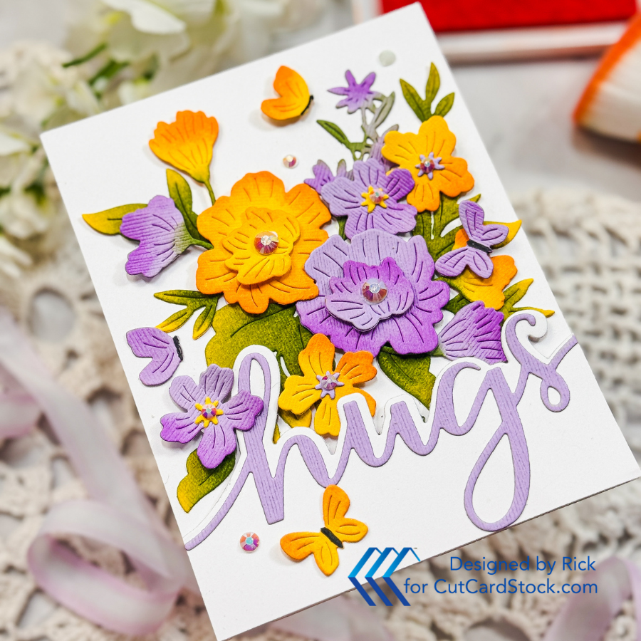 Colorful card with orange and purple flowers and butterflies. The word "hugs" is written in purple script. Background is soft and floral.