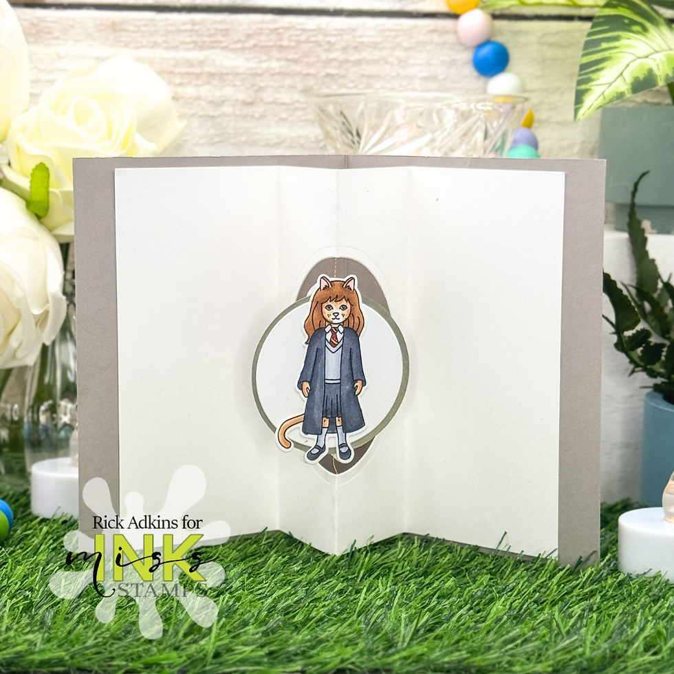 Greeting card with a cartoon cat character in school attire. White roses and colorful garland in the background, on a grassy surface.