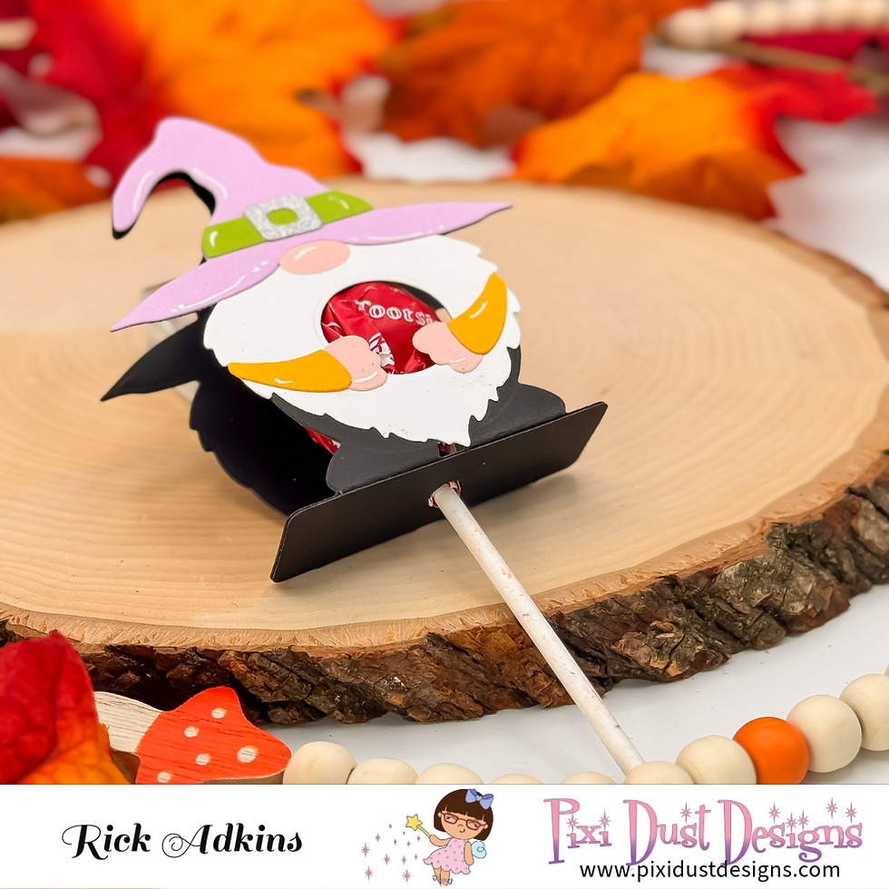 Gnome-themed candy holder with "Tootsie" label, on wood slice, surrounded by fall leaves. Text: "Rick Adkins, Pixi Dust Designs". Playful vibe.