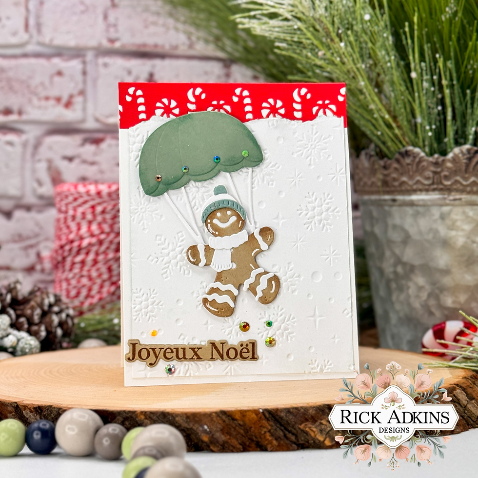 Gingerbread man on a snowy card parachuting with a green canopy. Text: Joyeux Noël. Background: festive decor, red and white accents.