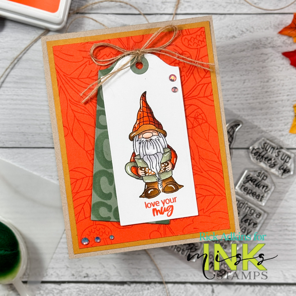 Card featuring a gnome on a white tag with "love your mug" text. Background is orange with leaf patterns, accented by gems and a bow.