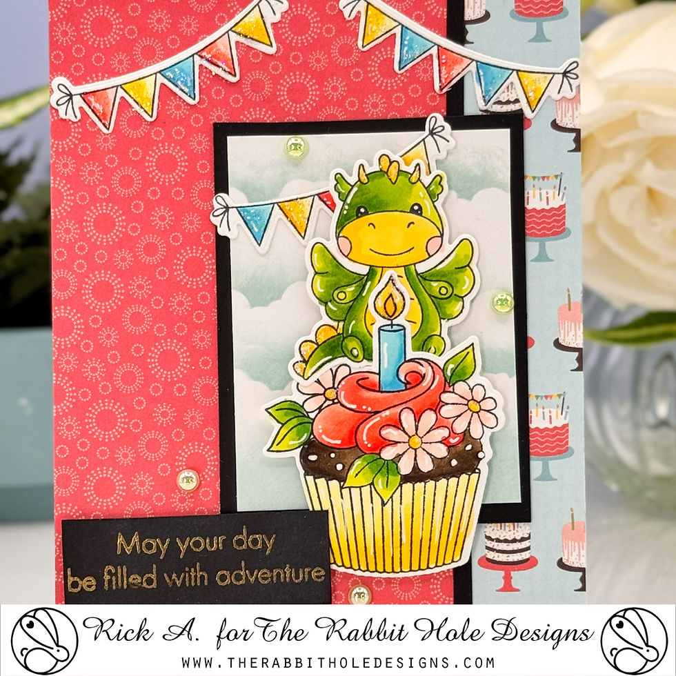 Cute dragon on cupcake with lit candle, surrounded by colorful buntings. Red patterned and blue background. Text reads "May your day be filled with adventure".