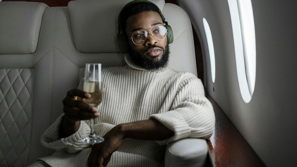 African American man relaxing in a private jet, sipping champagne and listening to music.