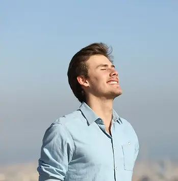 A calm man standing outdoors with eyes closed, breathing deeply and finding emotional balance through internal family systems therapy.