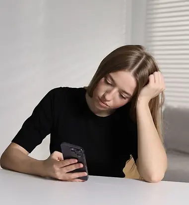 Young woman looking at her phone with concern, reflecting the need for social anxiety treatment.