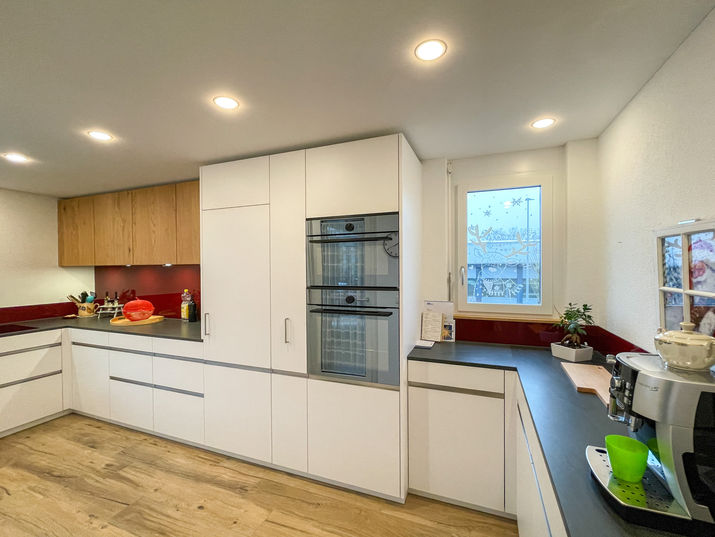 Moderne Eleganz trifft Funktionalität – Unsere Küchenreferenzen

Mit Liebe zum Detail und einem klaren Blick für Design durften wir diese moderne Küche gestalten. Klare Linien, hochwertige Materialien und ein harmonisches Farbkonzept machen diesen Raum zu einem Highlight. Die Kombination aus weißen Fronten und warmem Holz schafft eine natürliche Balance, während die rote Glasrückwand einen kraftvollen, modernen Akzent setzt.

Besonderheiten dieser Küche:

Optimierter Stauraum: Die intelligenten Auszugssysteme bieten maximalen Komfort und erleichtern die Organisation.
Hochwertige Materialien: Robuste Arbeitsflächen und präzise verarbeitete Fronten garantieren eine langlebige Nutzung.
Perfekte Beleuchtung: Eingebaute Deckenspots setzen die Arbeitsfläche optimal in Szene und schaffen ein helles, freundliches Ambiente.
Ob gemütliches Frühstück oder kreatives Dinner – diese Küche ist ein Ort, an dem Funktionalität und Ästhetik aufeinandertreffen. Lassen Sie sich von unseren Referenzen inspirieren und kontaktieren Sie uns, um Ihre Traumküche zu realisieren.

Ihr Projekt. Unsere Leidenschaft.