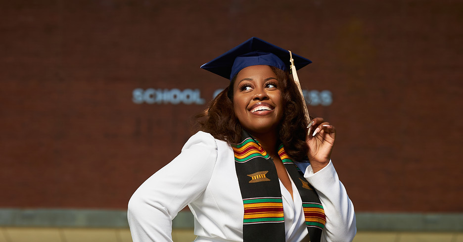 Jaelyn's Graduation Picture. She is in a white suit with her graduation cap, posing in front of Howard University.