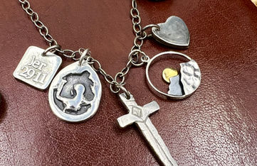A Multi-Token necklace with 5 handmade sterling silver charms. A necklace celebrating one's faith journey is represented with custom designs made just for the wearer.