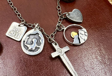 A Multi-Token necklace with 5 handmade sterling silver charms. A necklace celebrating one's faith journey is represented with custom designs made just for the wearer.