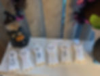 6 cookies in the shape of ghosts with happy faces. Each cookies has a letter on it which spells out SPOOKY. A happy witch is in the background.