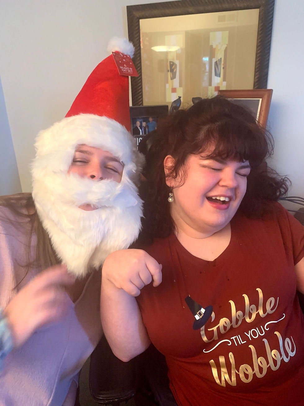 Photo of my cousin Kalyn in a Santa hat and beard and me wearing my Thanksgiving shirt that says gobble til you wobble.