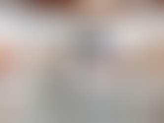 Clothes on a silver conveyor in a gallery, with large portraits on white walls. Bright, colorful garments hang from the circular rack.