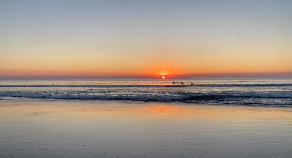sunset on a calm evening over the pacific ocean with surfers enjoying the view