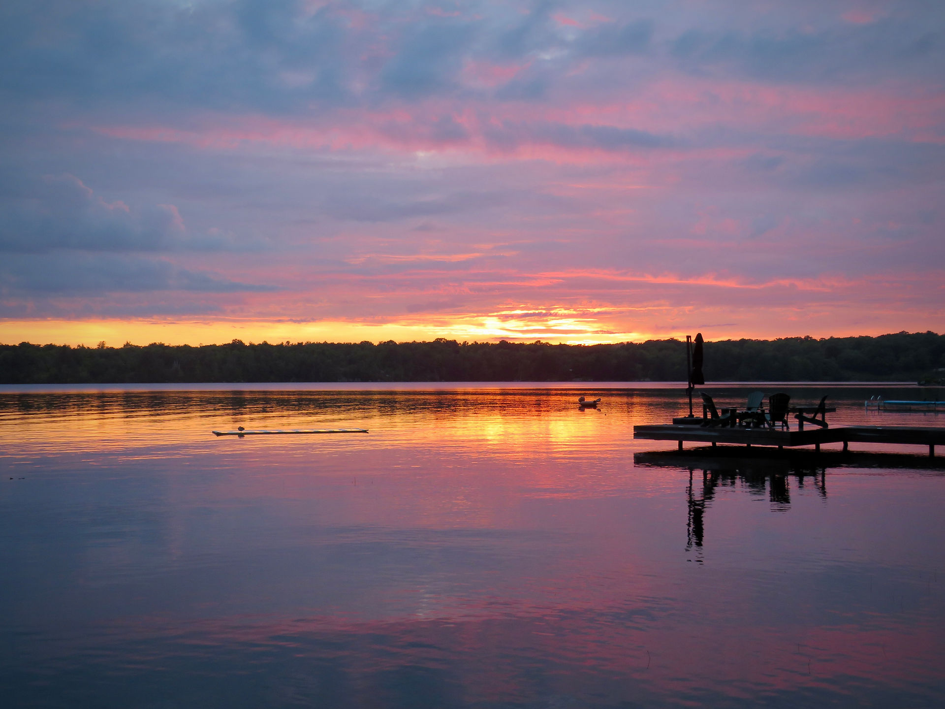 Colourful sunset reflecting on a lake, dock silhouette on the side
