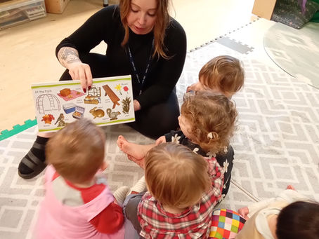 Storytime at Kidz Kabin nursery and a team member is reading a book to a group of four children