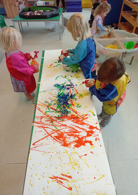 Toddlers painting together on a long table at Shropshire Hall Nursery Kidz Kabin
