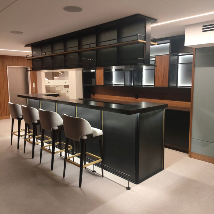 Diseño de lujo de un bar a medida en una cocina abierta. Todos los gabinetes cuentan con luz perimetral. La gama de colores es muy neutra: negro, beige, grises y café. Hay cuatro sillas altas grises.