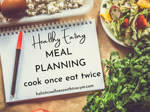 a meal and herbs in the background with a pen and a notebook that reads Meal Planning cook once eat twice