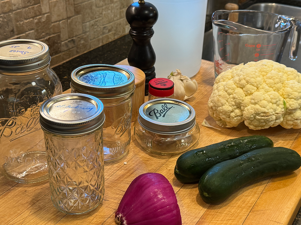 pickle ingredients along with canning jars on a wooden cutting board.