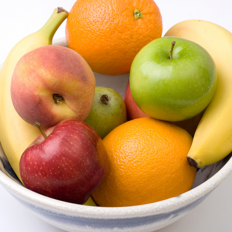 fruit bowl containing apples, peaches, oranges and bananas