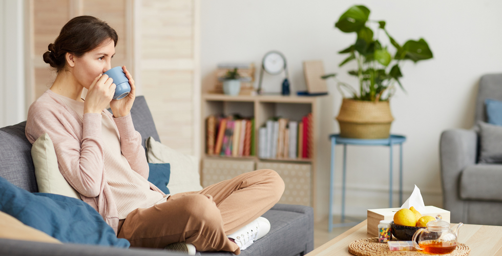 A woman relaxing on a blue chair while drinking tea