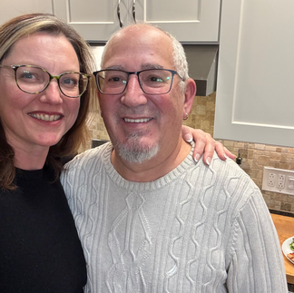 Tracy and Andrew standing in kitchen with plate of pizza on counter behind them