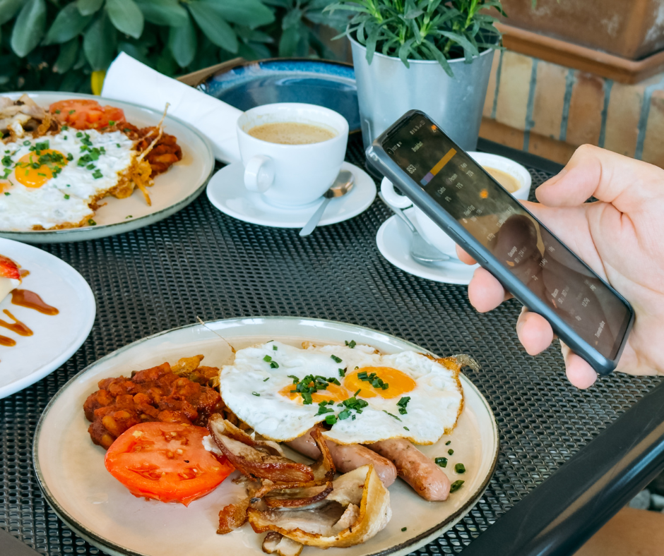 a table with plates of food and someone entering the information into a calorie tracking app