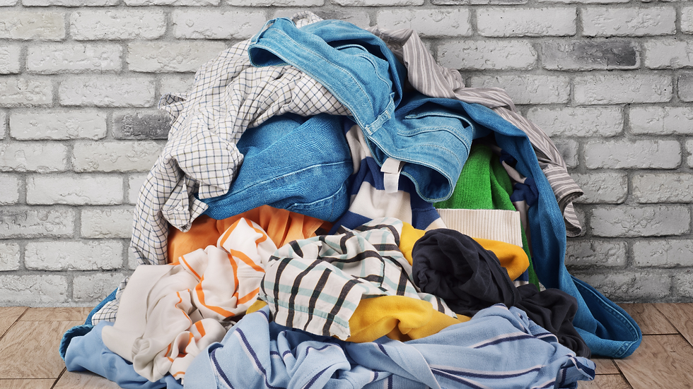 pile of laundry on the floor in front of a white brick wall