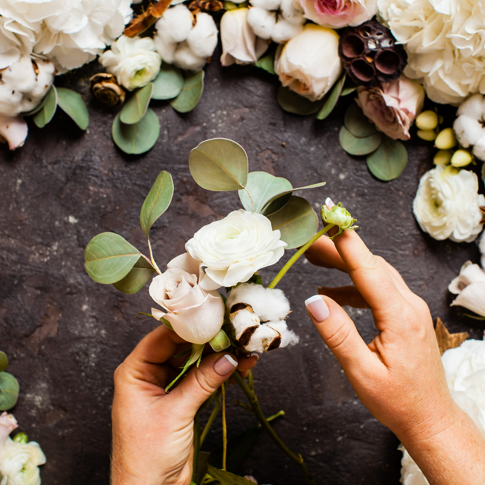 hands arranging white flowers over concrete table