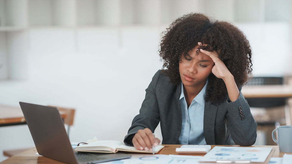 Young African-American Woman at her desk looking worried.