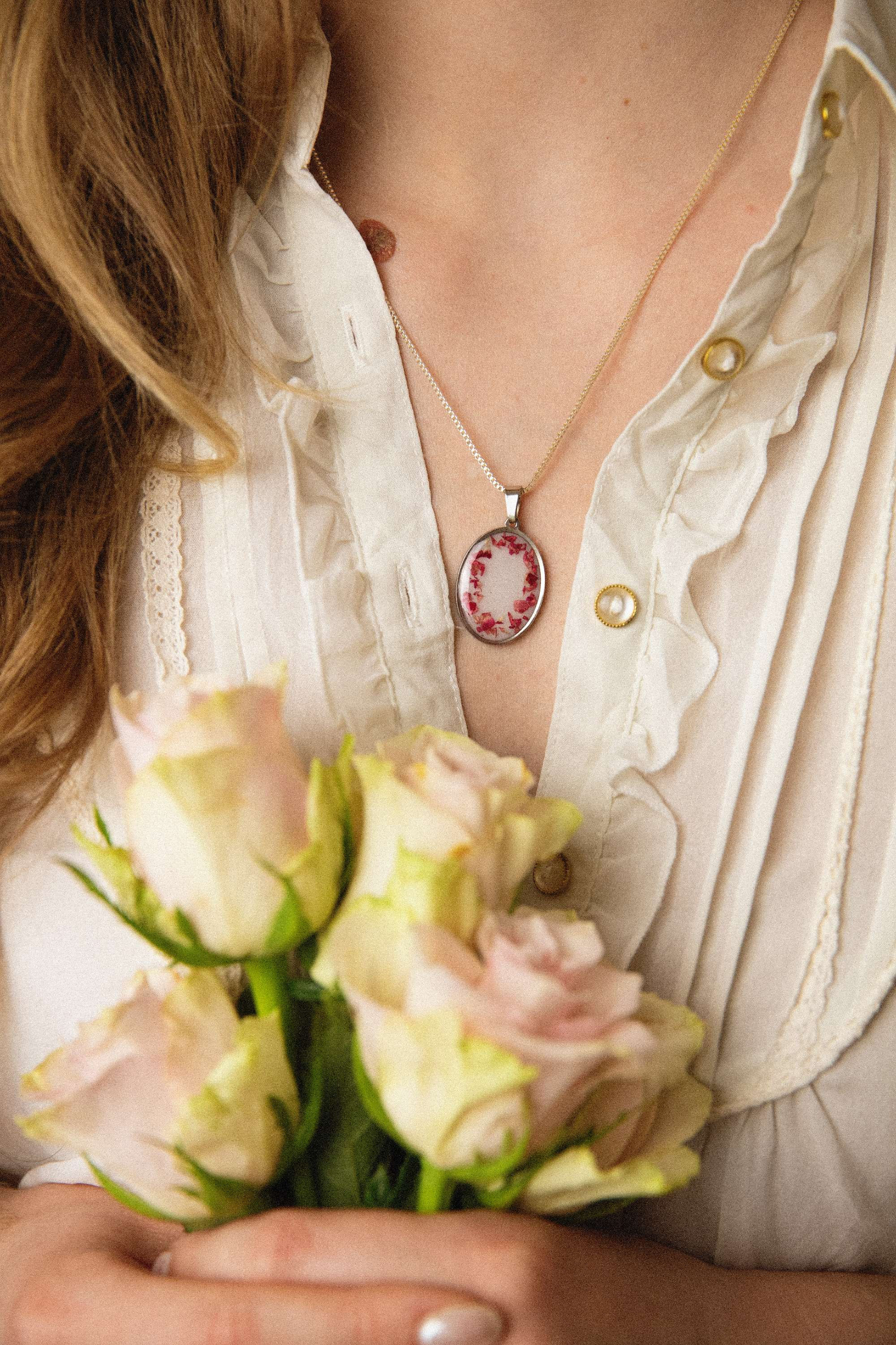 Collier argenté avec brisures de pétale de rose sur fond blanc porté