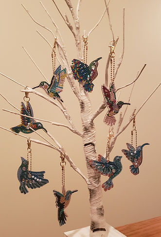Eight Hummingbird Diamond Painting Key Chains hanging on a Fake Birch Tree