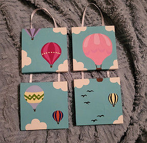 Four small canvases with two sets attached by ribbon, that are painted with balloons, clouds and birds.