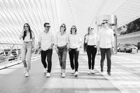 Cinq collaborateurs marchant côte à côte sous la gare de Liège-Guillemins, photo en noir et blanc – par Julien Stevens Photography