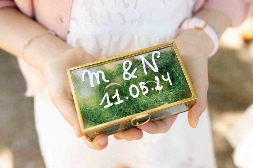 Boîte à alliances en verre gravée “M & N - 11.05.24” tenue dans les mains de la mariée – par Julien Stevens Photography
